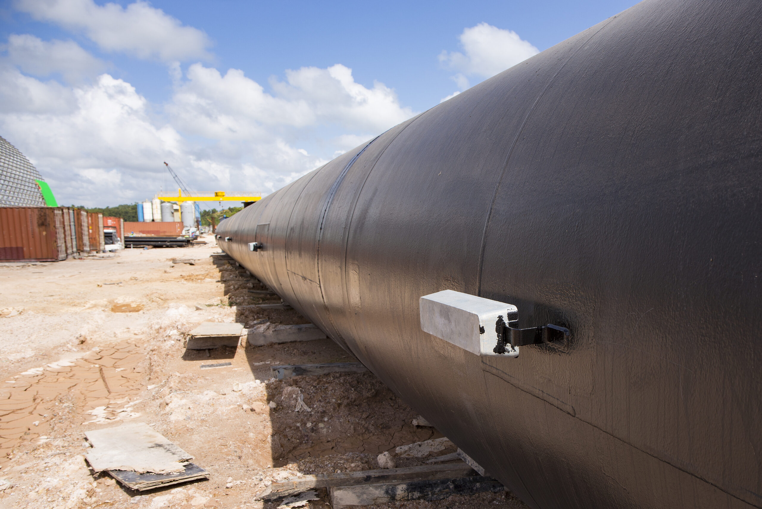 A large black industrial pipeline with magnesium anodes installed, illustrating the application of cathodic protection systems to prevent corrosion.
